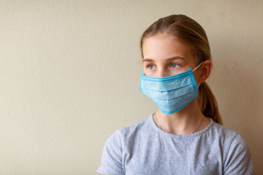 Little teenage girl in medical mask sad and scared. Coronavirus protection, wearing masks concept