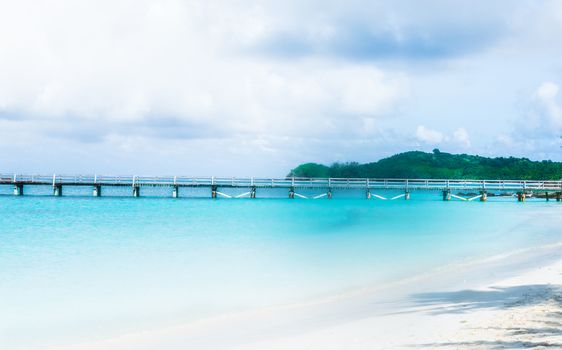 Dreamy photo of a dock stretching out into the Pacific Ocean from  a Yasawa-I-Rara beach.