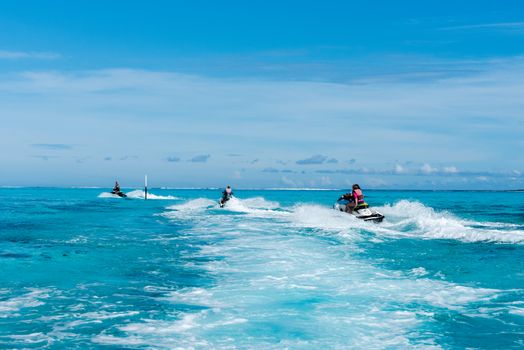 Moorea Island, French Polynesia--March 17, 2018. Jet ski riders skim over the waters of a blue lagoon off the coast of Moorea Island. Editorial use only.