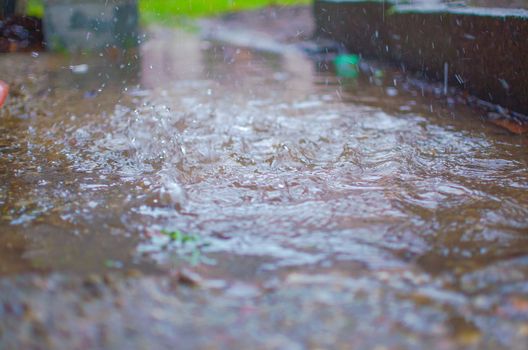 Drops of heavy rain on sidewalk surface. Rain water on the surface of the flood the sidewalk on the city street.