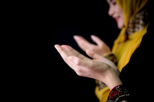 religious young Muslim two women praying over black background.