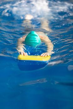 Cute little girl training in a swimming pool. Swimming sport for kids concept