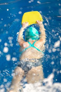 Cute little girl training in a swimming pool. Swimming sport for kids concept