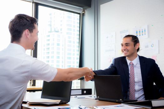 Two happy successful business partner shaking hands in the office.