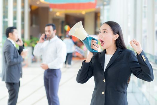 Young business woman working at the office, 
shouting and yelling in megaphone