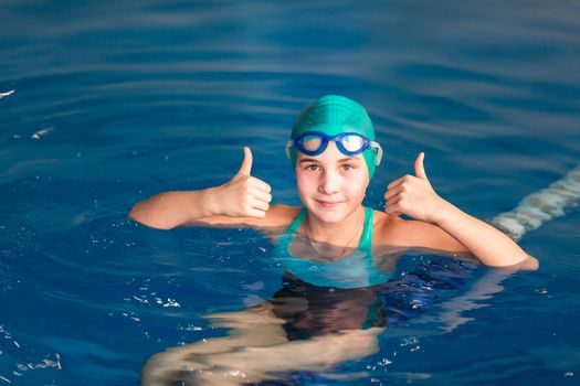 Cute little girl training in a swimming pool. Swimming sport for kids concept