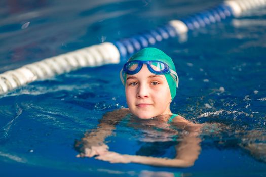 Cute little girl training in a swimming pool. Swimming sport for kids concept