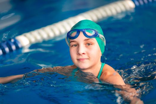 Cute little girl training in a swimming pool. Swimming sport for kids concept