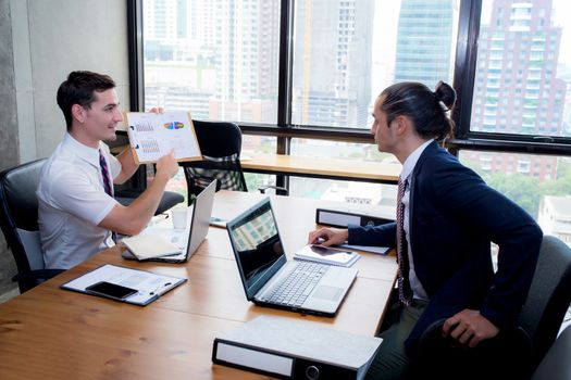 Business people discussing the charts and graphs showing the results of their successful teamwork in meeting room.