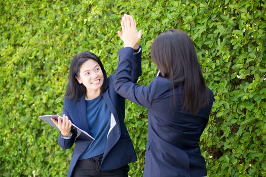 Businesswoman two people high fiving outdoors nature background.