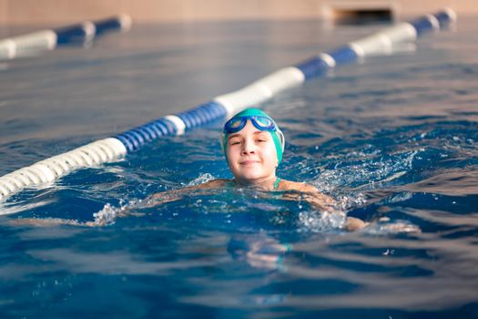 Cute little girl training in a swimming pool. Swimming sport for kids concept