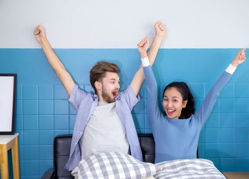 Cute loving couple is with gesture in sofa - man and woman are sitting smiling and glad with success.