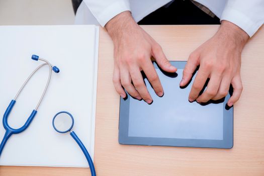 male doctor with tablet computer and stethoscope at the desk on white background.