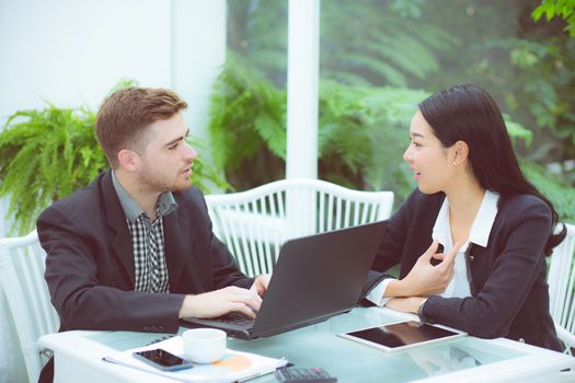 Couple of young business working at modern office, two coworkers discussing fun project over a laptop.