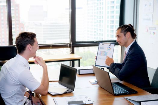 Business people discussing the charts and graphs showing the results of their successful teamwork in meeting room.