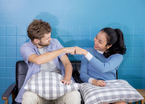 Young couple of man and woman with family on sofa - Fist bump.