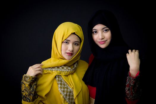 Portrait of two beautiful muslim asian woman having fun together isolated over black background, Portrait two beautiful happy muslim woman,Age 20-30 years.