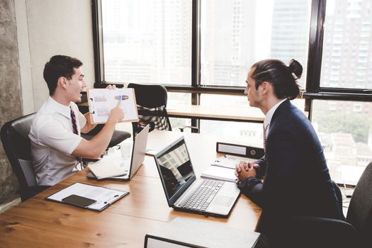 Business people discussing the charts and graphs showing the results of their successful teamwork in meeting room.