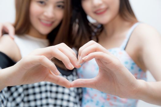 Two woman twins showing heart shape with hands closeup.