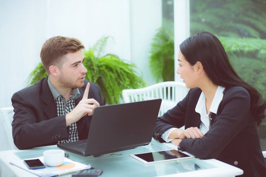 Couple of young business working at modern office, two coworkers discussing fun project over a laptop.