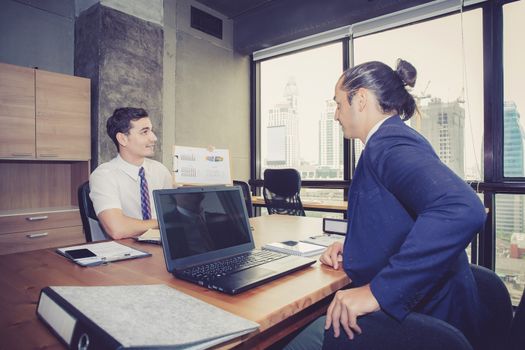 Business people discussing the charts and graphs showing the results of their successful teamwork in meeting room.