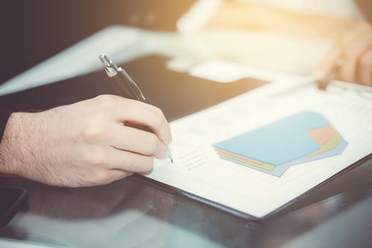 Closeup of business partners hands over document with charts and graph of male and woman hand with pens in meeting room.