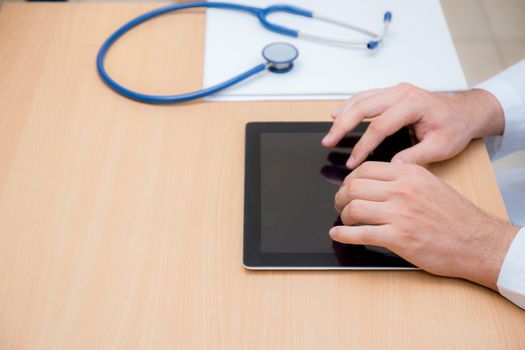 male doctor with tablet computer and stethoscope at the desk on white background.