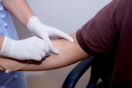 nurse putting an IV needle into a patients hand.