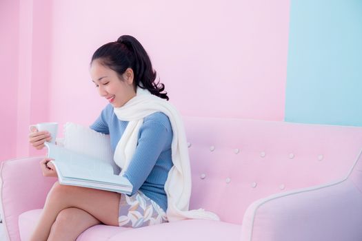 Beautiful young woman is reading book and holding a cup of coffee with in room retro pastel style.