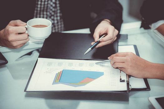 Closeup of business partners hands over document with charts and graph of male and woman hand with pens in meeting room.