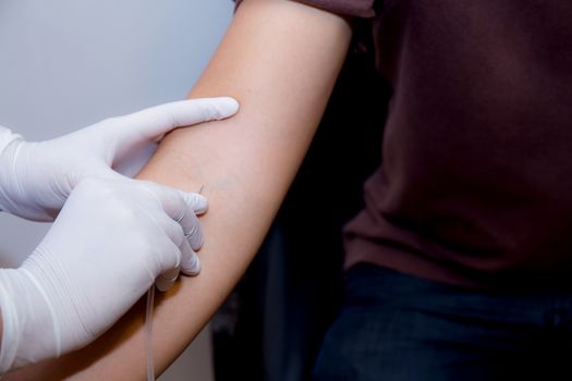 nurse putting an IV needle into a patients hand.