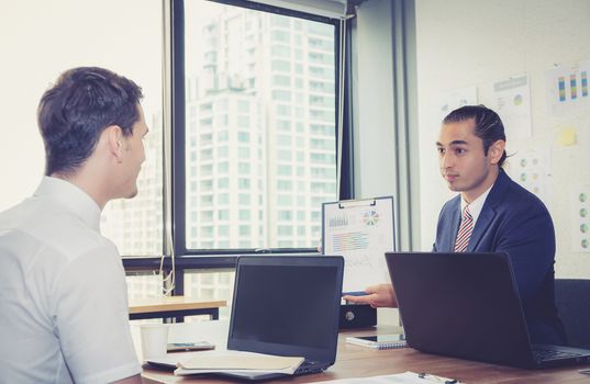 Business people discussing the charts and graphs showing the results of their successful teamwork in meeting room.