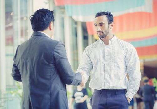 two businessmen shaking hands on outdoors.