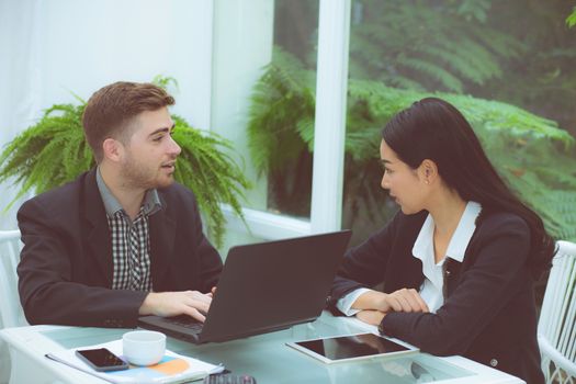 Couple of young business working at modern office, two coworkers discussing fun project over a laptop.