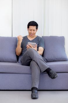 businessman watching media content in a tablet sitting on a sofa at home.