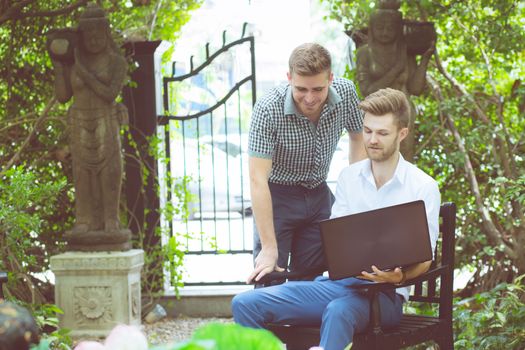 Two business people use of the notebook computer at outdoor.