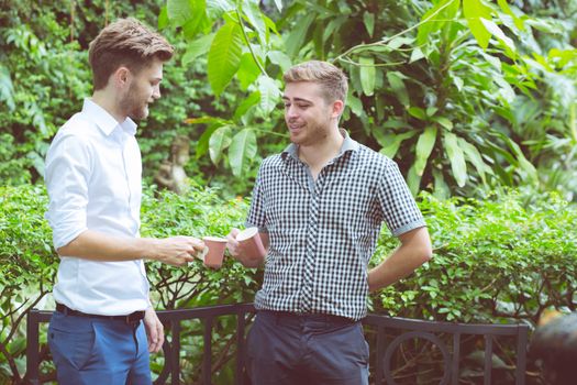 Two friends men talking standing in a garden.