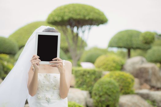 Asian bride woman holding and show digital tablet feeling so happiness.