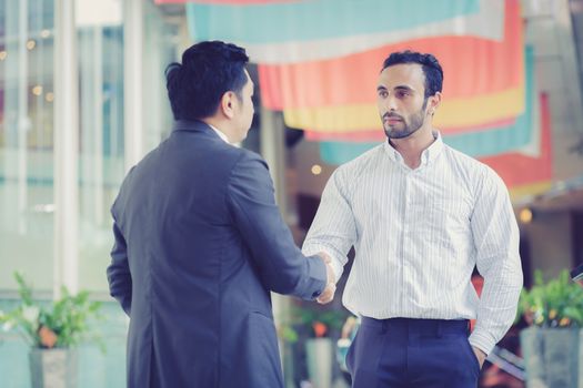 two businessmen shaking hands on outdoors.