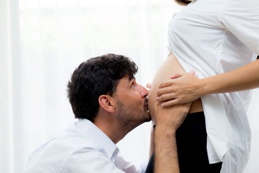 close up husband kiss pregnant woman belly - love of father to the unborn child.