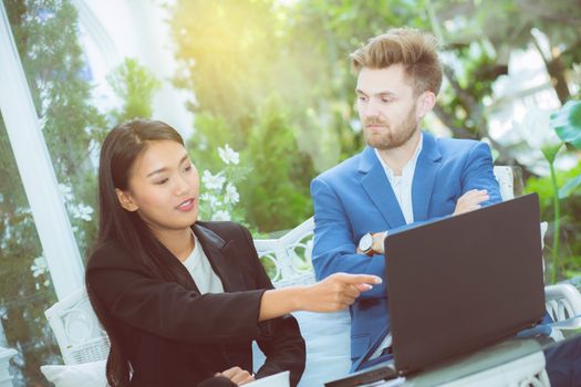 technology and office concept - two business man and woman with laptop - tablet pc computer and papers having discussion in office.