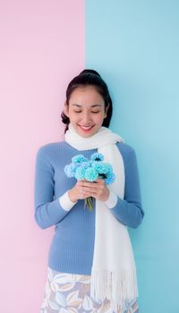 Happy beautiful young woman asian holding flower on living room pastel color tone.