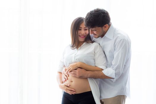 Pregnant Mother and father standing hugging holding belly, family concept.