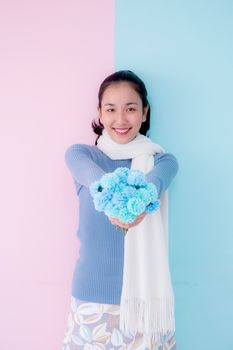 Happy beautiful young woman asian holding flower on living room pastel color tone.