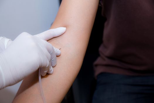 nurse putting an IV needle into a patients hand.