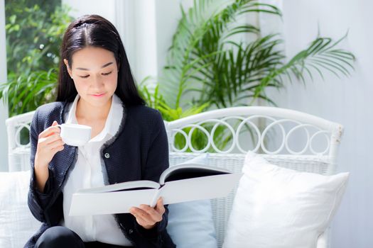 Young businesswoman sitting at table in coffee shop and reading book.