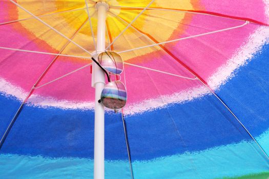 beach umbrella and sunglasses against the sea horizon and clear sky