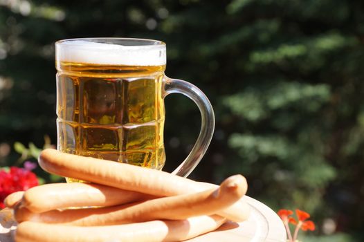 glass mug with beer and sausages on a background of nature on a sunny day