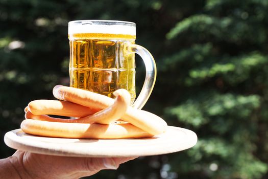 glass mug with beer and sausages on a background of nature on a sunny day