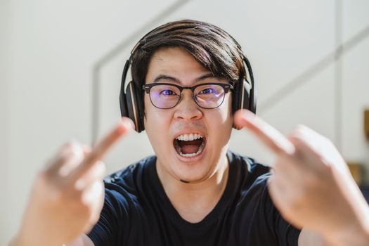 Asian Man showing thumbs up sign Fuck when he angry in stay from home at covid19 pandemic, serious expression when work from home, doing fucking off to camera, social distancing concept